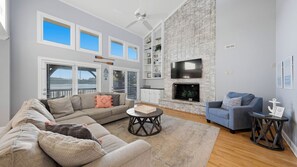 A living room with a fireplace, a sofa, a coffee table, and a TV mounted on the wall.