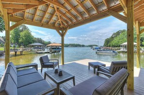 A covered outdoor seating area with wooden furniture and a view of the water. - Dock Holiday by Avantstay Custom Home + New Dock (Huntersville)