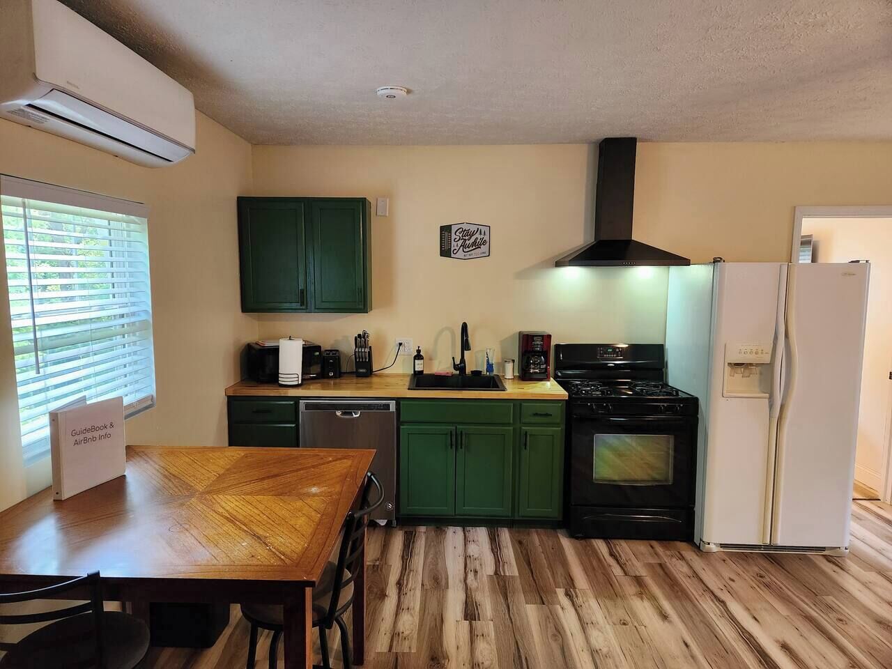 A compact kitchen with green cabinets, a black stove, and a white refrigerator.