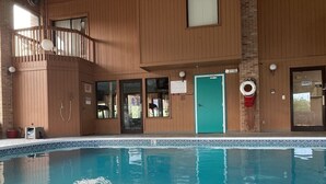 En inomhuspool med ett trädäck, en grön dörr och en livboj.