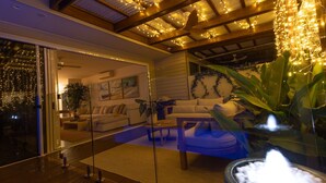 A modern living room with a glass door leading to a balcony, a sofa, a coffee table, and a large plant.