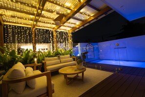 An outdoor seating area with a sofa and table, surrounded by plants and string lights. - Luxury Tri-Level Duplex in Mermaid Beach (Mermaid Beach)