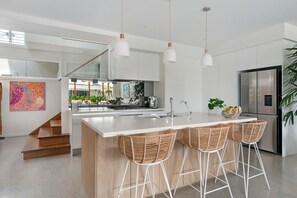 A modern kitchen with a central island, stainless steel appliances, and a staircase leading to an upper level.