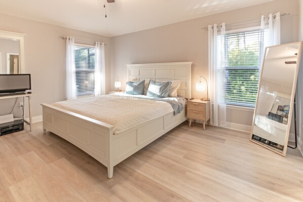 A bedroom with a bed, bedside tables, a TV, and a mirror.