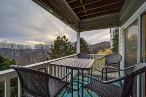 Relax in this serene outdoor seating area with a table and four chairs, surrounded by a white railing and breathtaking mountain views.