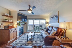 Cozy living room with a fireplace, leather sofa, and sliding glass door offering a view of the outdoors.