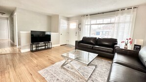 A modern living room with a flat-screen TV, leather sofa, and a glass coffee table.