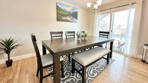 A dining area with a wooden table, four chairs, a bench, and a potted plant.