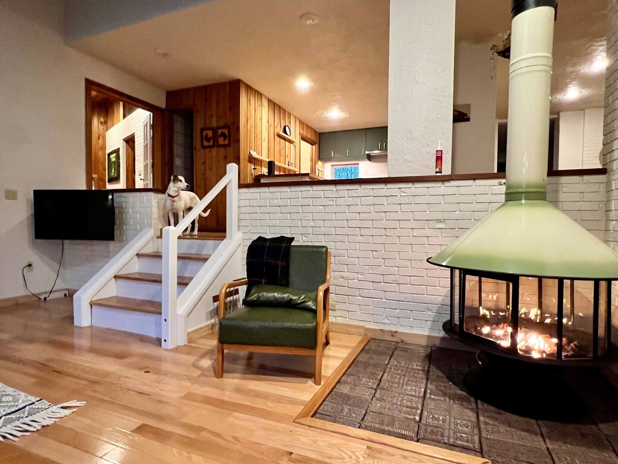 Una sala de estar con chimenea, una escalera y una cocina al fondo.