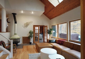 A living room with a fireplace, a sofa, a coffee table, and large windows. - Spacious Hidden Gem in Athens OH (Athens)