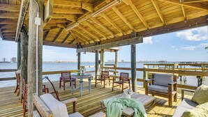 Een houten terras met buitenmeubilair, een tafel en uitzicht op het water.