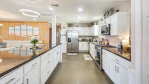 Een moderne keuken met witte kasten, roestvrijstalen apparatuur en een centraal eiland met een marmeren aanrecht.