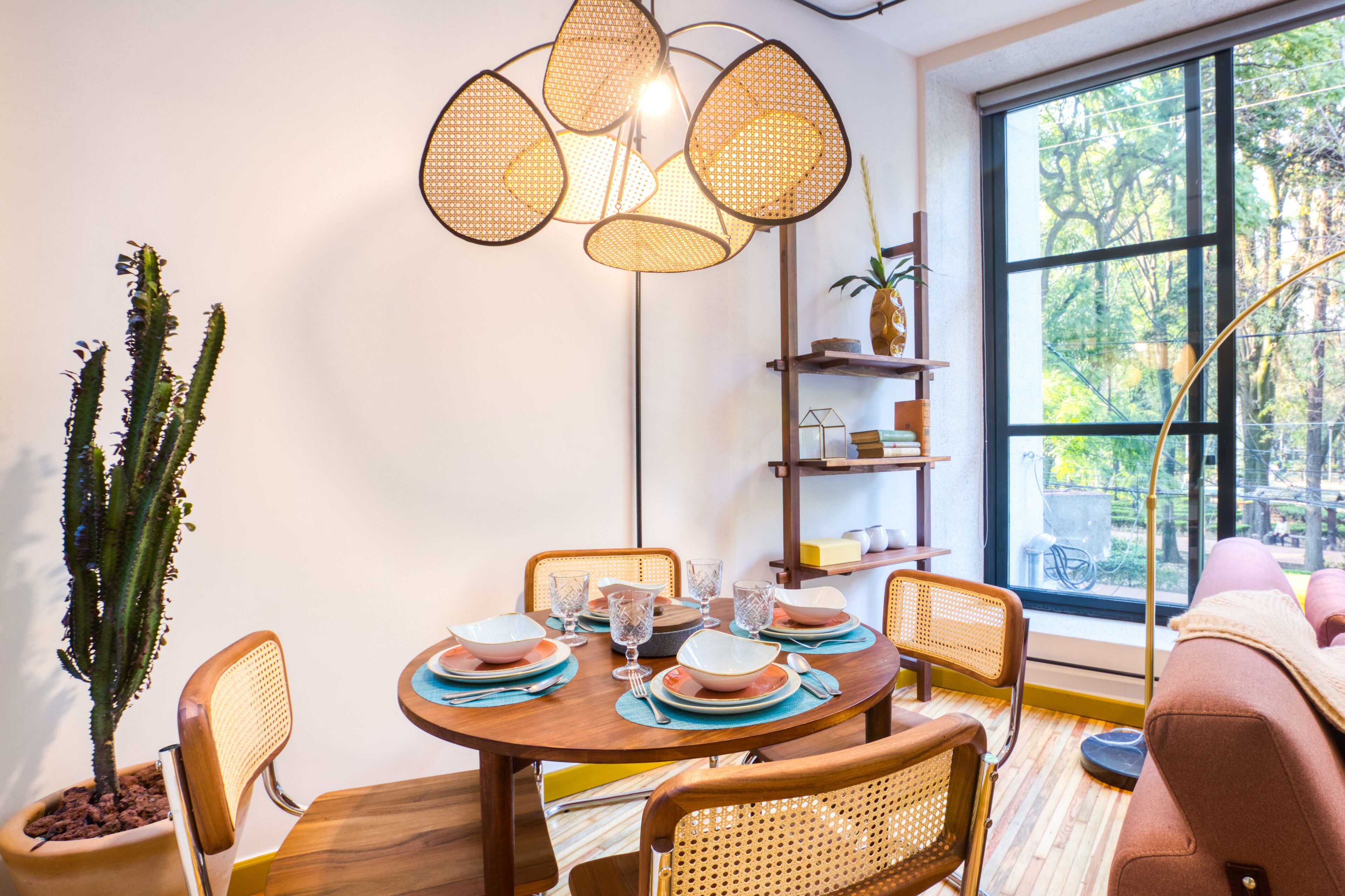 A dining area with a round wooden table, wicker chairs, and a modern pendant light fixture.