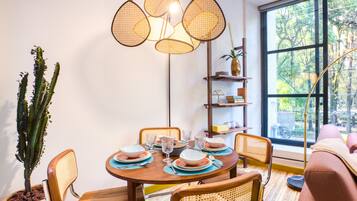 A dining area with a round wooden table, wicker chairs, and a modern pendant light fixture.