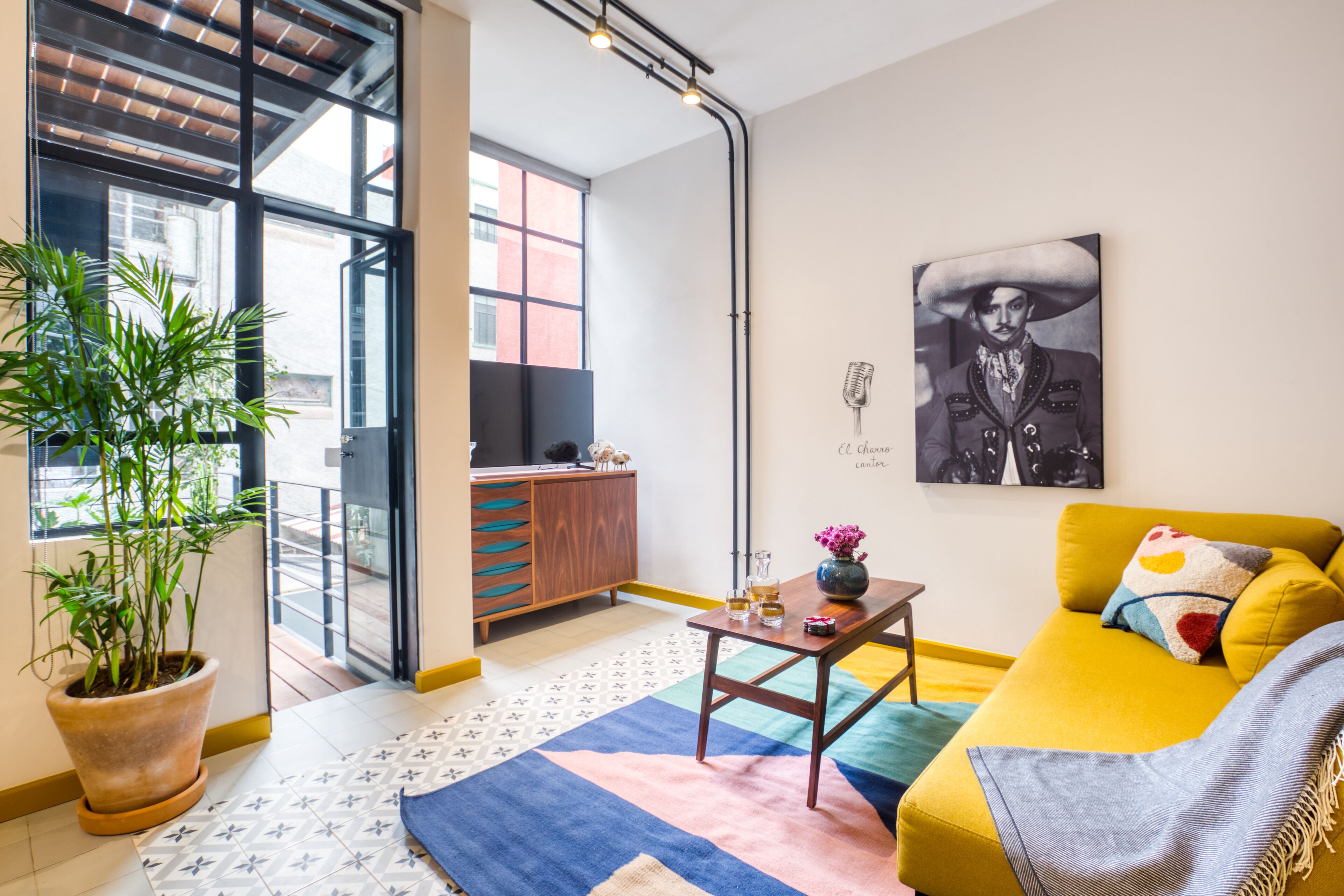 Una sala de estar moderna con un sofá amarillo, una mesa de centro y una planta en maceta.