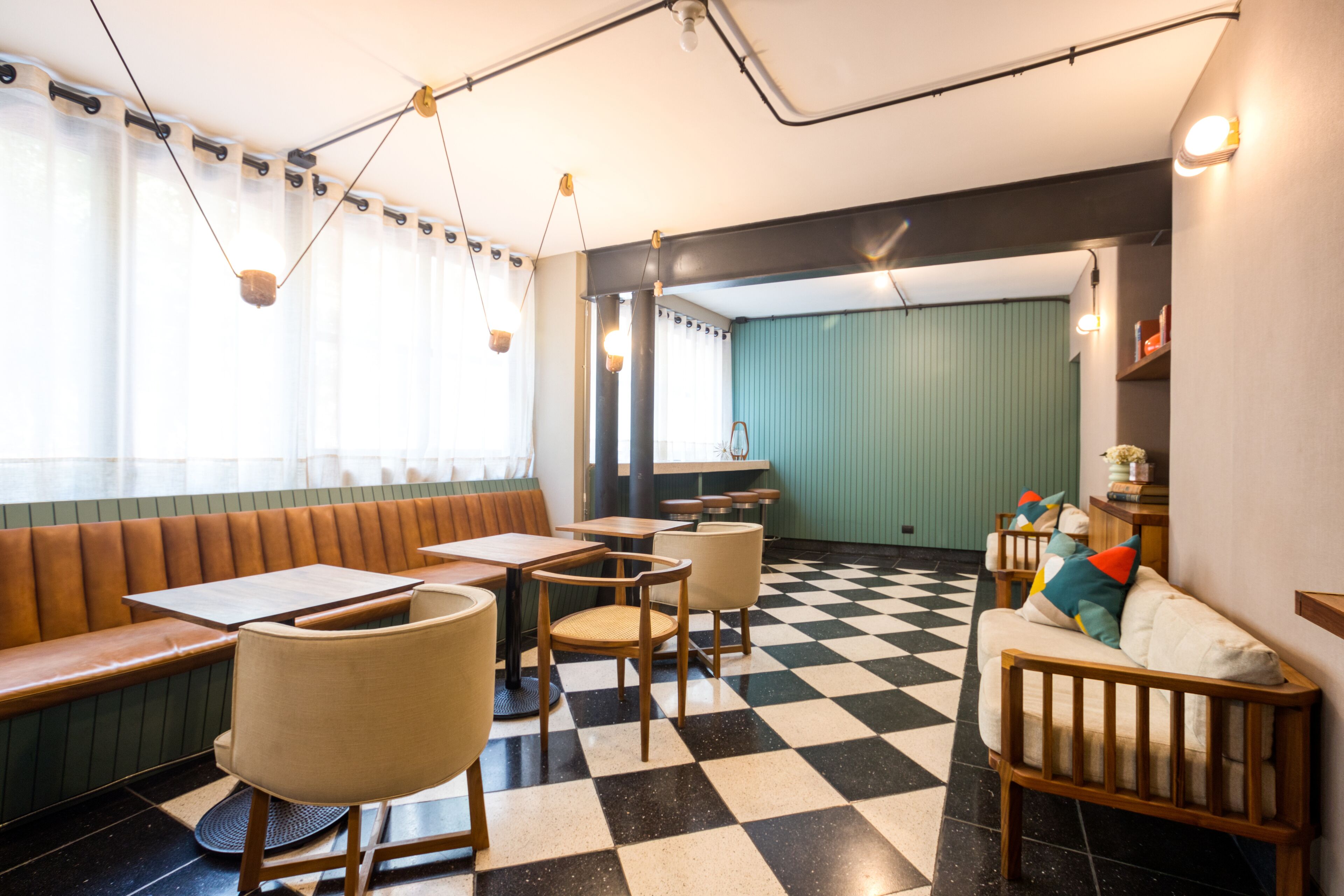 Ein Restaurantinneres mit Schachbrettfußboden, Holzmöbeln und Pendelleuchten.