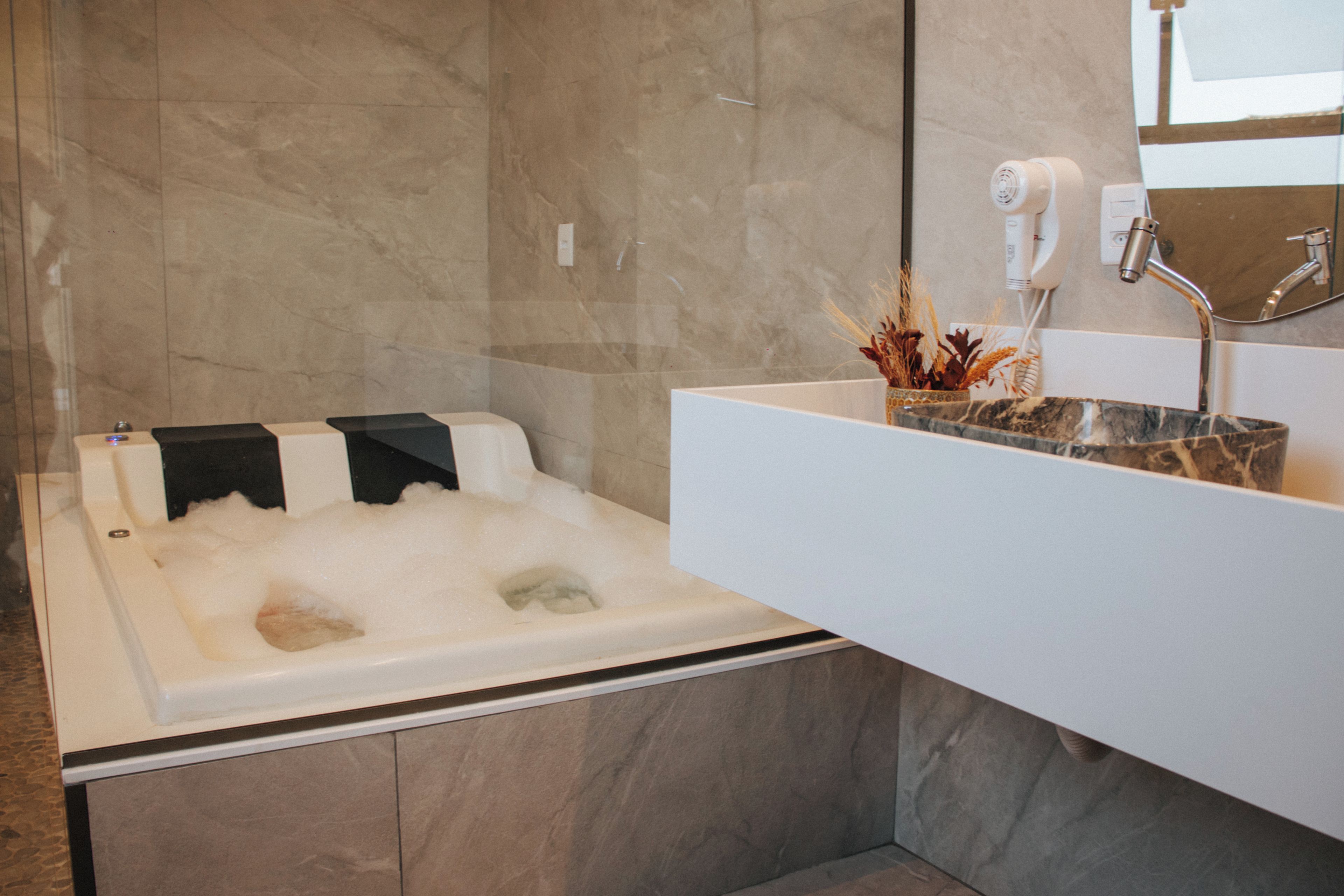 A modern bathroom with a bathtub, a white sink, and a mirror.