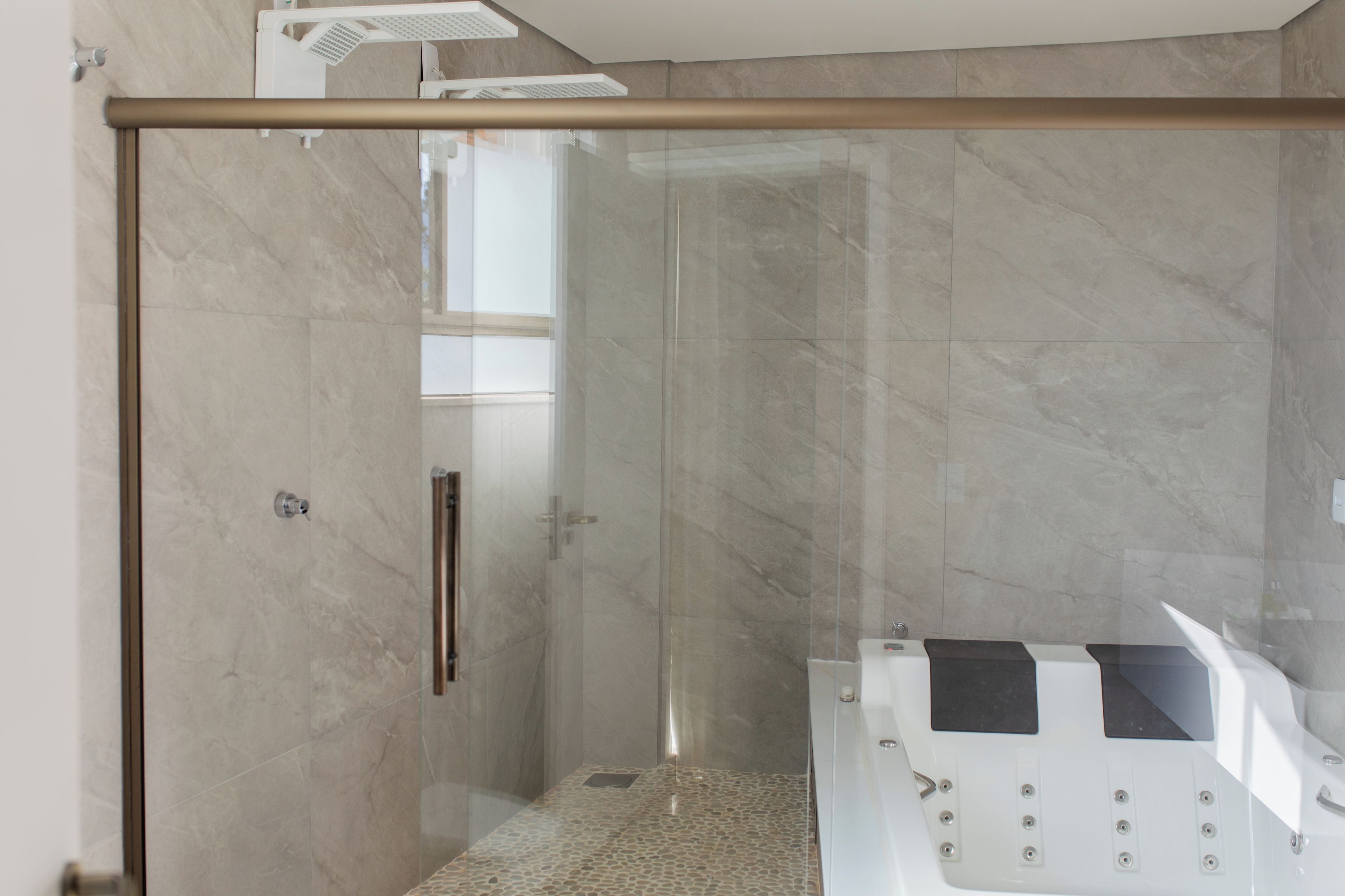Un baño moderno con cabina de ducha de vidrio, una bañera blanca y suelo de mármol.