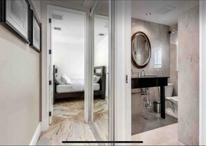 A modern bathroom with a marble floor, a large mirror, and a black sink.