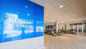 A hotel lobby with a large blue sign reading "AQUA ALOHA SURF". - Waikiki Ocean View Deluxe Studio (Honolulu)