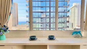 A kitchen with a view of tall buildings, two bowls on the counter, and a vase with flowers. - Waikiki Ocean View Deluxe Studio (Honolulu)