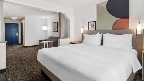 Una habitación de hotel con una cama grande, un escritorio, una silla y una puerta.