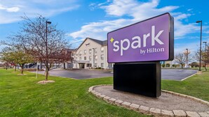 Letrero de hotel con el nombre "Spark by Hilton" y un edificio al fondo.