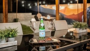 Ein Tisch im Freien mit einer Pellegrino-Flasche, zwei Gläsern und einer Platte mit Speisen.
