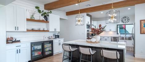 Una cocina moderna con armarios blancos, una isla central con taburetes y una lámpara colgante.