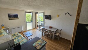 Habitación pequeña con cama, escritorio, silla, mesa y televisor.