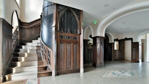 Eine imposante Treppe mit hölzernem Geländer und einer verzierten Tür am oberen Ende.