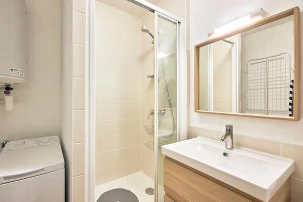 A bathroom with a glass-enclosed shower, a white sink, and a mirror above it.