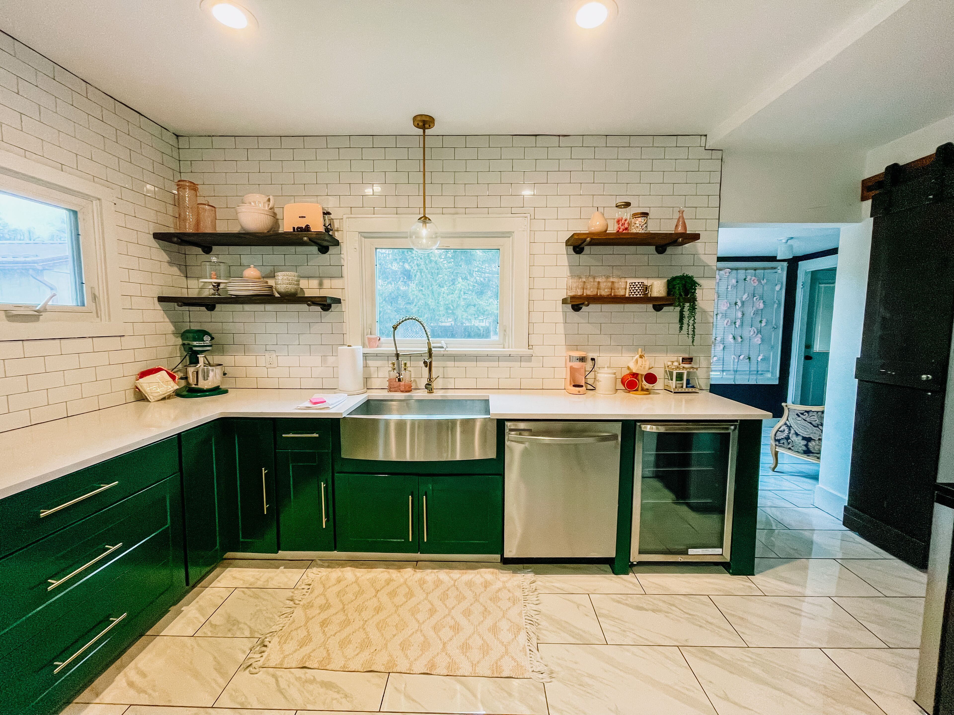 A modern kitchen with green cabinets, a stainless steel sink, and a window above the sink.