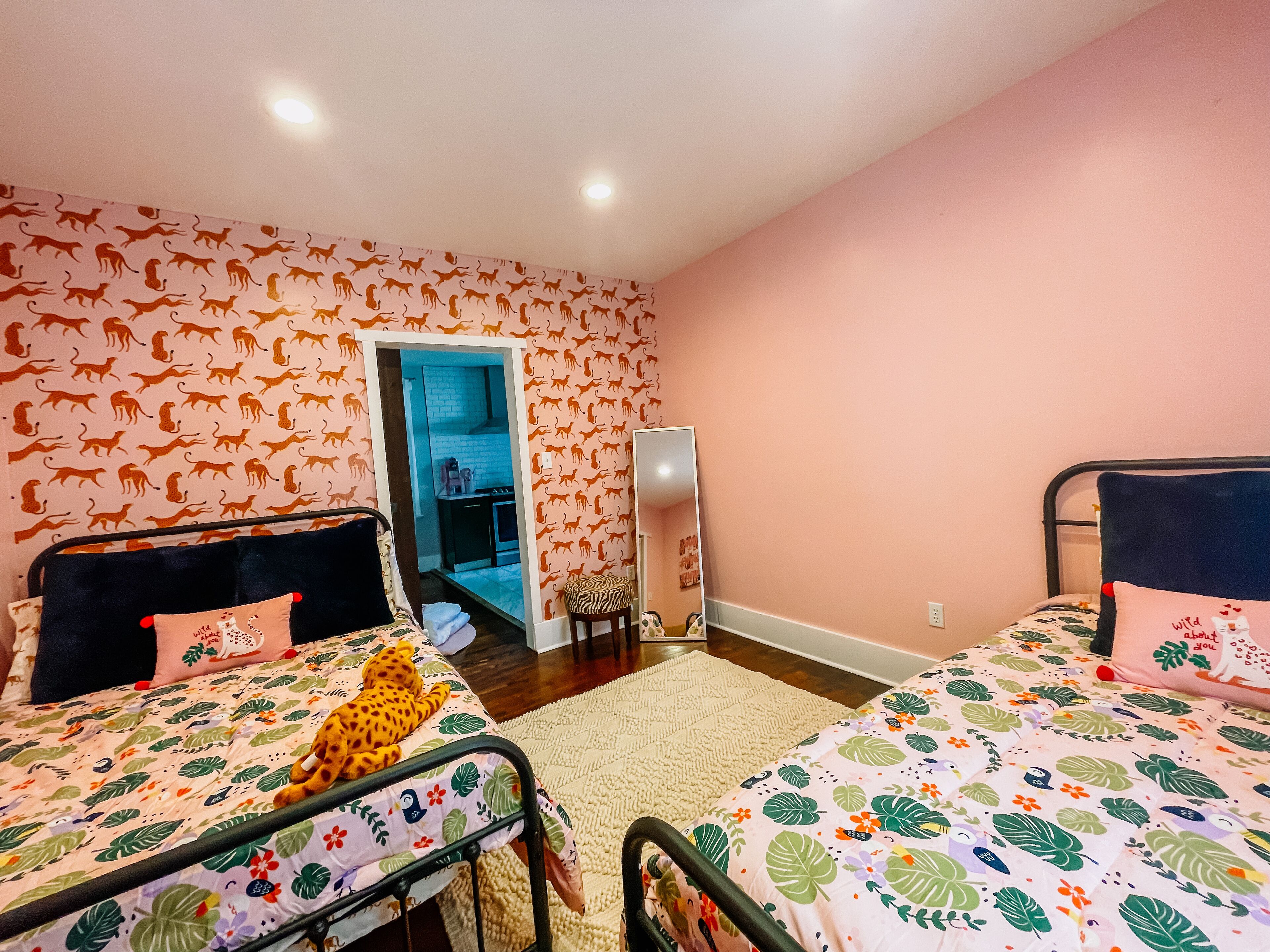 Un dormitorio con dos camas, un espejo y una puerta que da al baño.