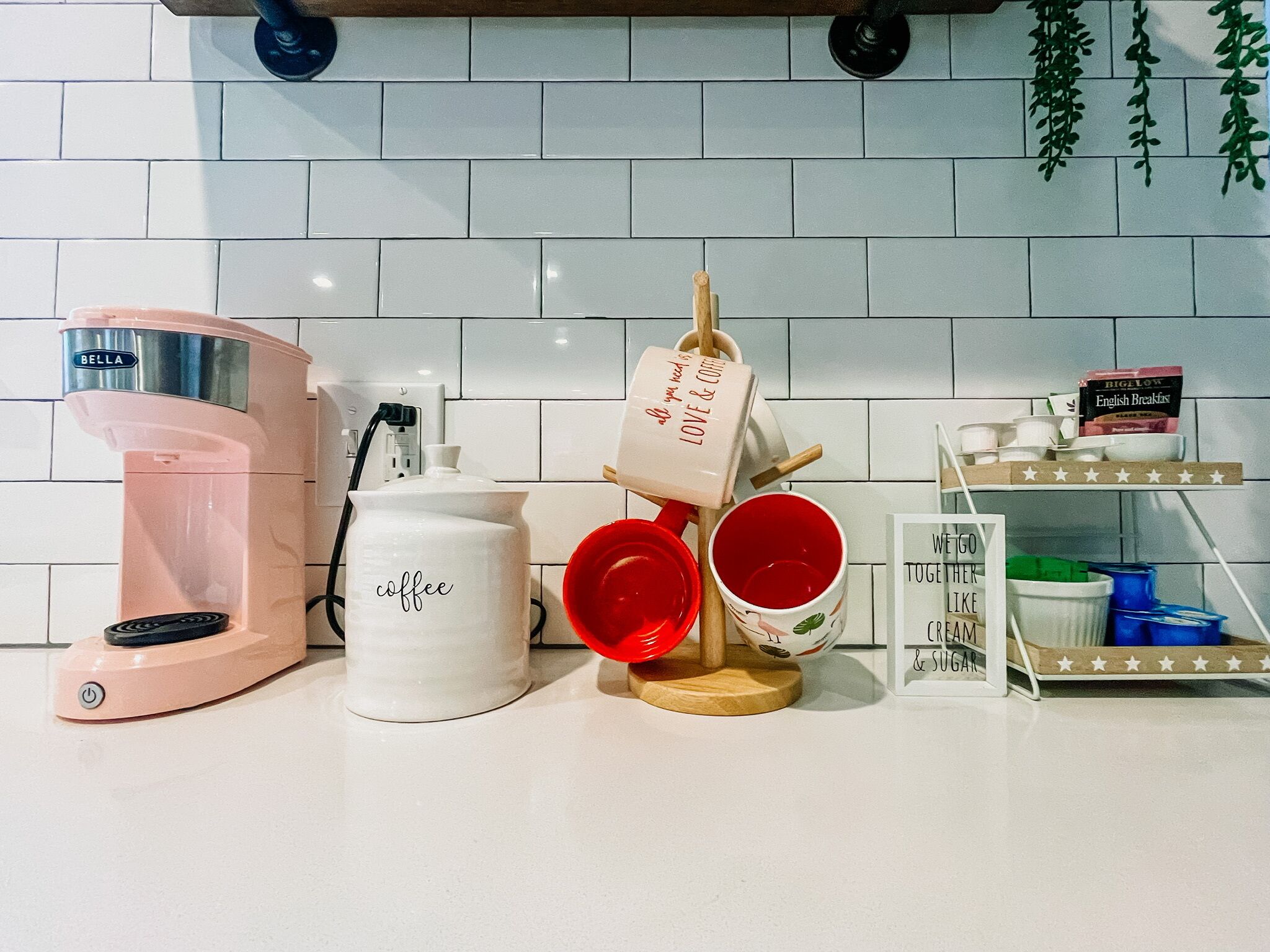 A kitchen counter with a coffee maker, a coffee pot, and a mug rack.