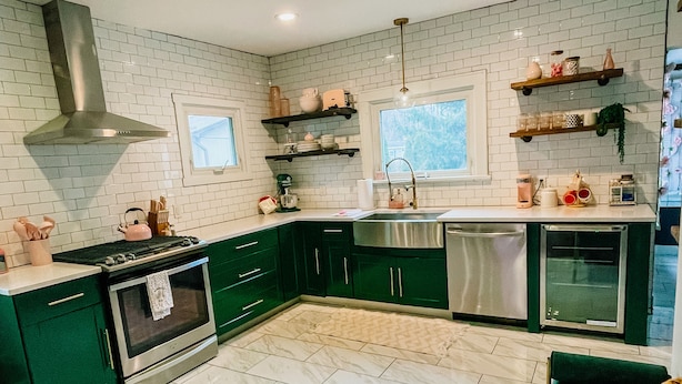 A modern kitchen with green cabinets, a stainless steel stove, and a built-in dishwasher.