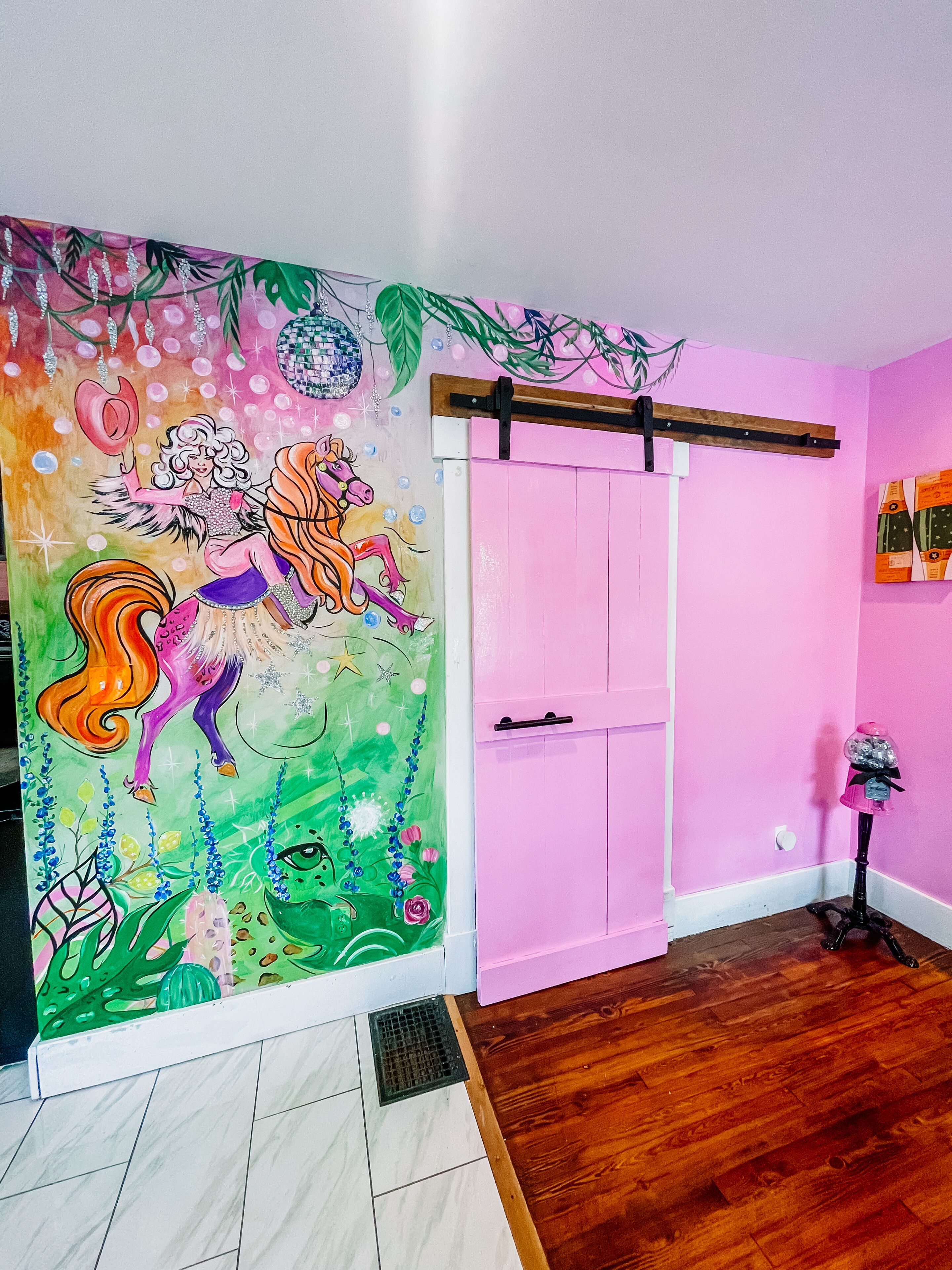 Et værelse med et farverigt muralmaleri, pink vægge og trægulv.