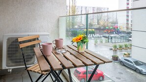 A balcony with a wooden table, two pink mugs, a vase with a yellow flower, and a white air conditioner. - Cozy studio 1st floor (București)