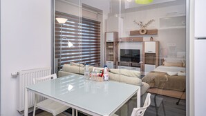 A modern living room with a glass table, a sofa, and a TV. - Cozy studio 1st floor (București)