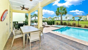 A covered outdoor area with a pool, patio furniture, and a grill.