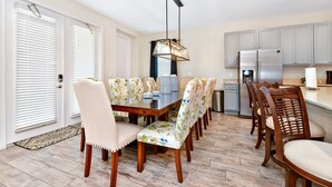Un comedor con una mesa de madera, sillas estampadas y una lámpara colgante moderna.