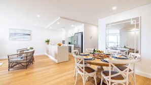 Una cocina moderna con una isla central, muebles blancos y un refrigerador de acero inoxidable.