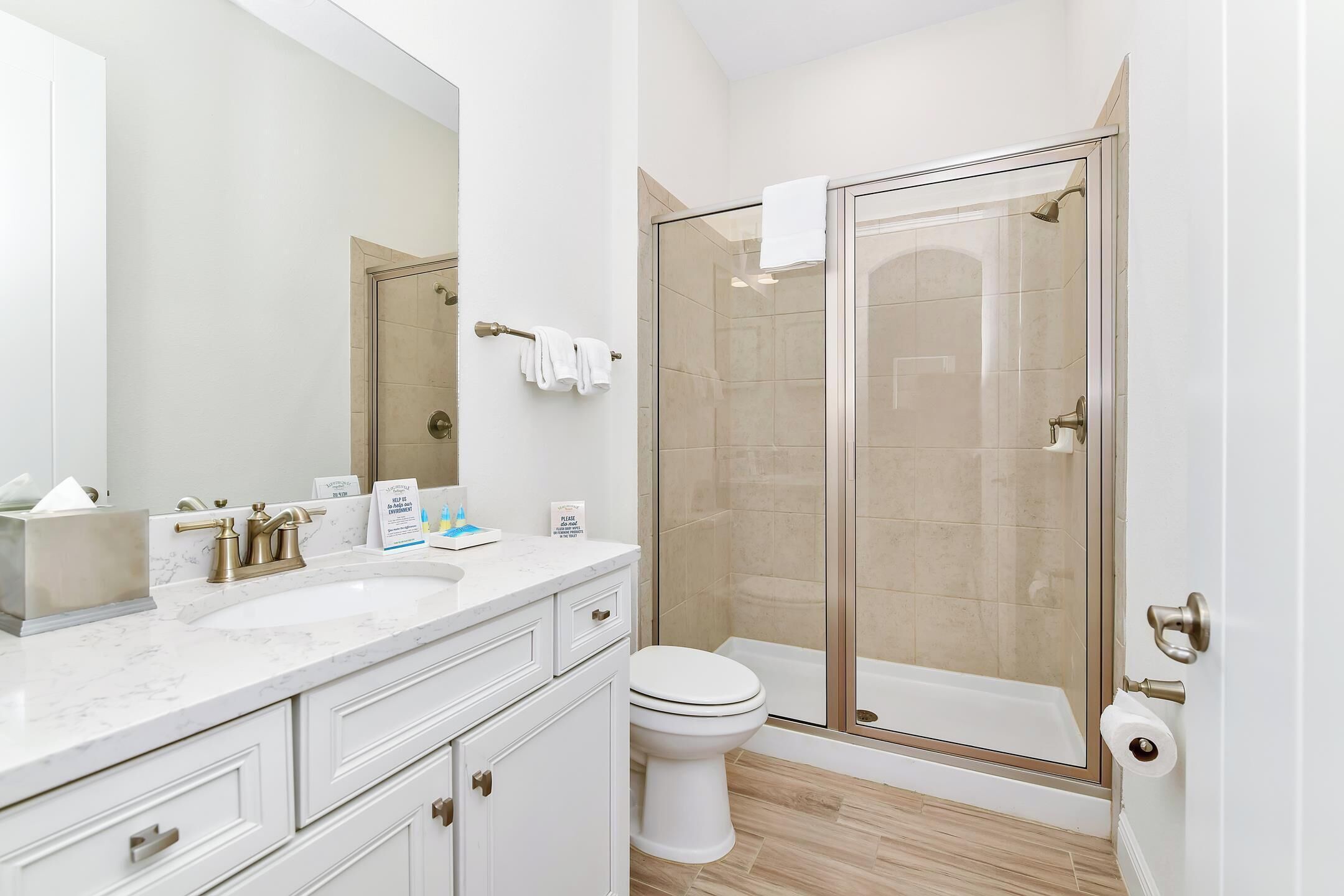 A modern bathroom with a glass-enclosed shower, a white toilet, and a marble sink.