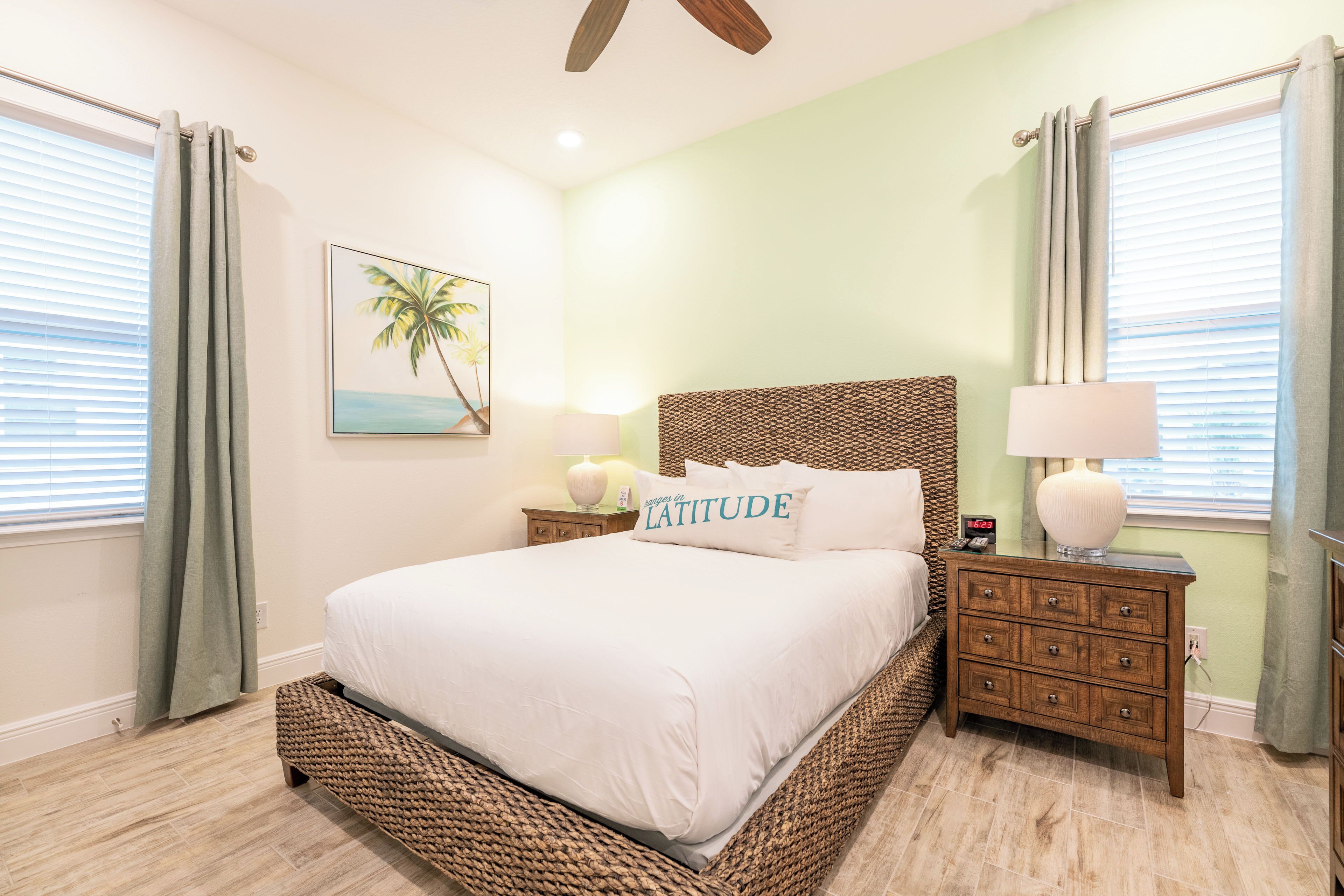 Un dormitorio con cama, mesitas de noche, una lámpara y un cuadro.