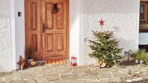 A building with a stone facade, a wooden double door, and a small Christmas tree with decorations.