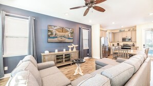 A modern living room with a gray sofa, a wooden cabinet, and a ceiling fan. - Spectacular Cottage near Disney w/ Pool & Island H2O Waterpark Access - 8026KD (Kissimmee)