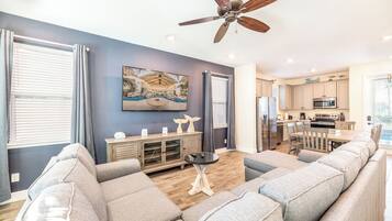 A modern living room with a gray sofa, a wooden cabinet, and a ceiling fan.