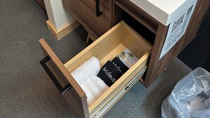 A bathroom with a white sink, black faucet, wooden cabinet, and a towel rack. - VRFLX Seneca View Bungalow | Hot Tub Retreat (Burdett)