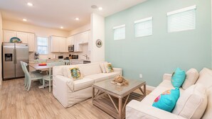 A modern kitchen with white cabinets, a refrigerator, and a dining area with a table and chairs.