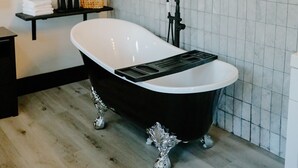 A modern bathroom with a freestanding bathtub, a potted plant, and neatly arranged towels on shelves.